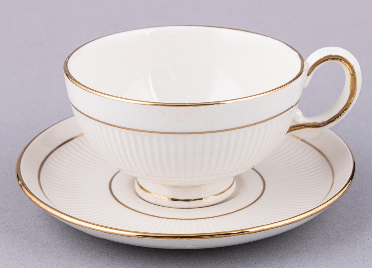 Kaffekopp med fat, flintgods. Modell AH, dekor Teneriffa.Vit glasyr med guldränder. Skapad av Arthur Percy för Gefle Porslinsfabrik 1943.
