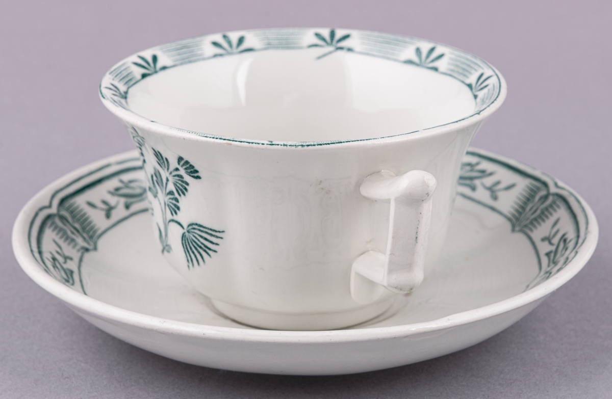 Kaffekopp med fat, i flintgods. Modell O, dekor Kerstin. Vit glasyr med grönt blommönster. Skapad av Arthur Percy för Gefle Porslinsfabrik 1933.