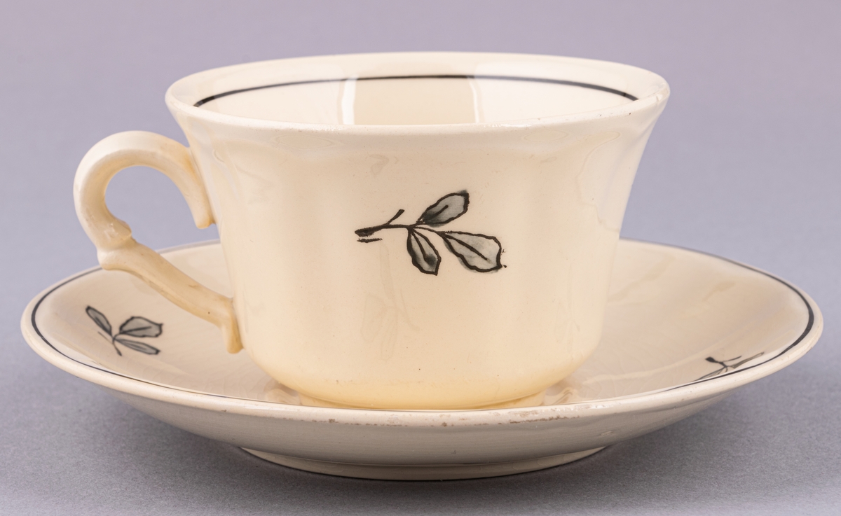 Kaffekopp med fat, i flintgods. Modell AK, dekor Bibo. Vit glasyr med flerfärgat blommönster. Skapad av Eugen Trost för Gefle Porslinsfabrik 1936.