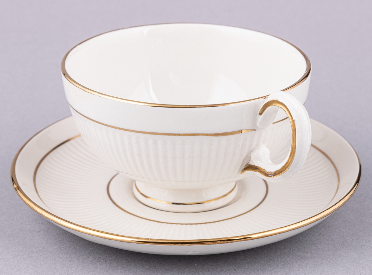 Kaffekopp med fat, flintgods. Modell AH, dekor Teneriffa.Vit glasyr med guldränder. Skapad av Arthur Percy för Gefle Porslinsfabrik 1943.