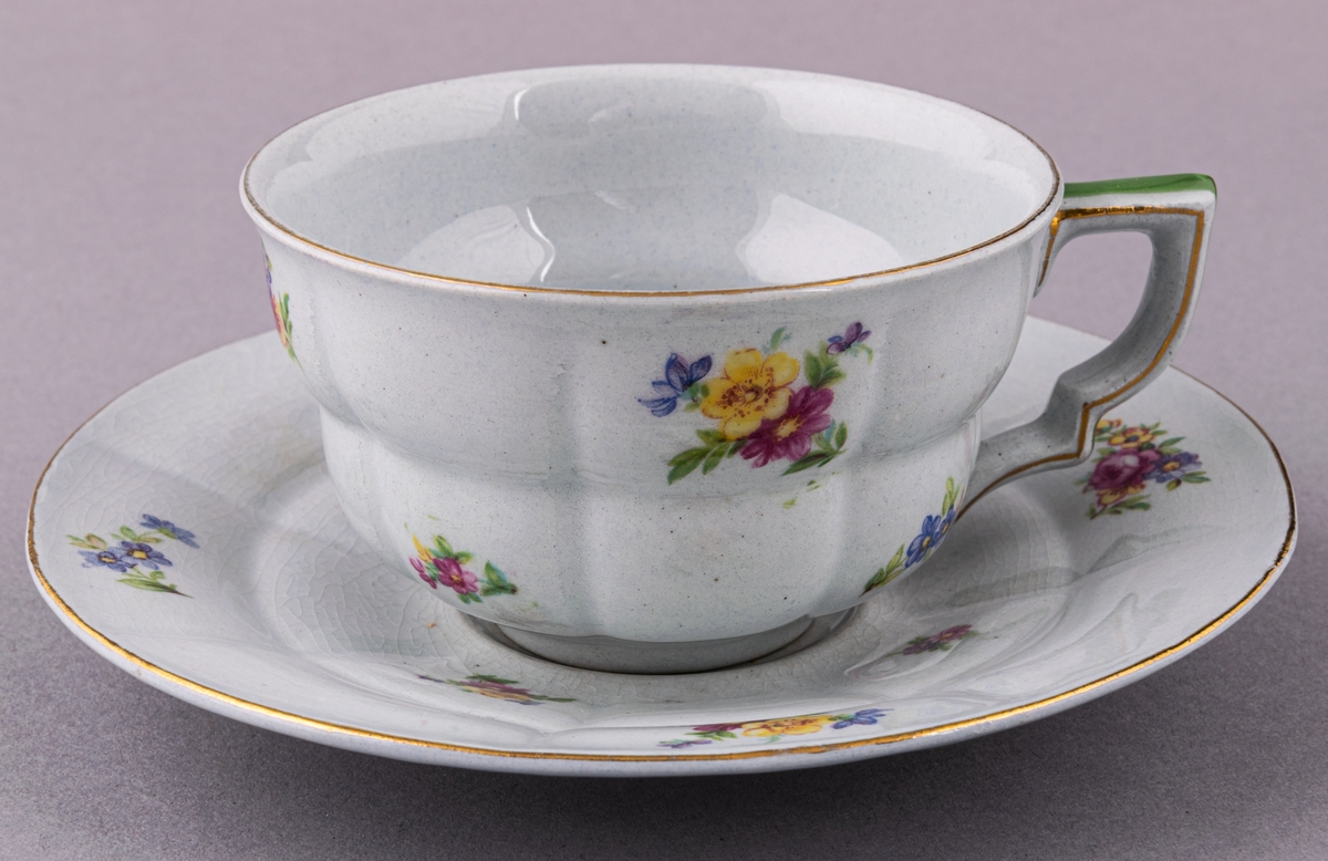 Kaffekopp med fat, i flintgods. Modelll AB, dekor Rosaslie. Ljusblå glasyr med blommönster. Skapad av Eugen Trost för Gefle Porslinsfabrik 1939.