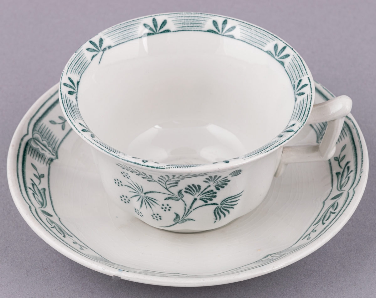 Kaffekopp med fat, i flintgods. Modell O, dekor Kerstin. Vit glasyr med grönt blommönster. Skapad av Arthur Percy för Gefle Porslinsfabrik 1933.