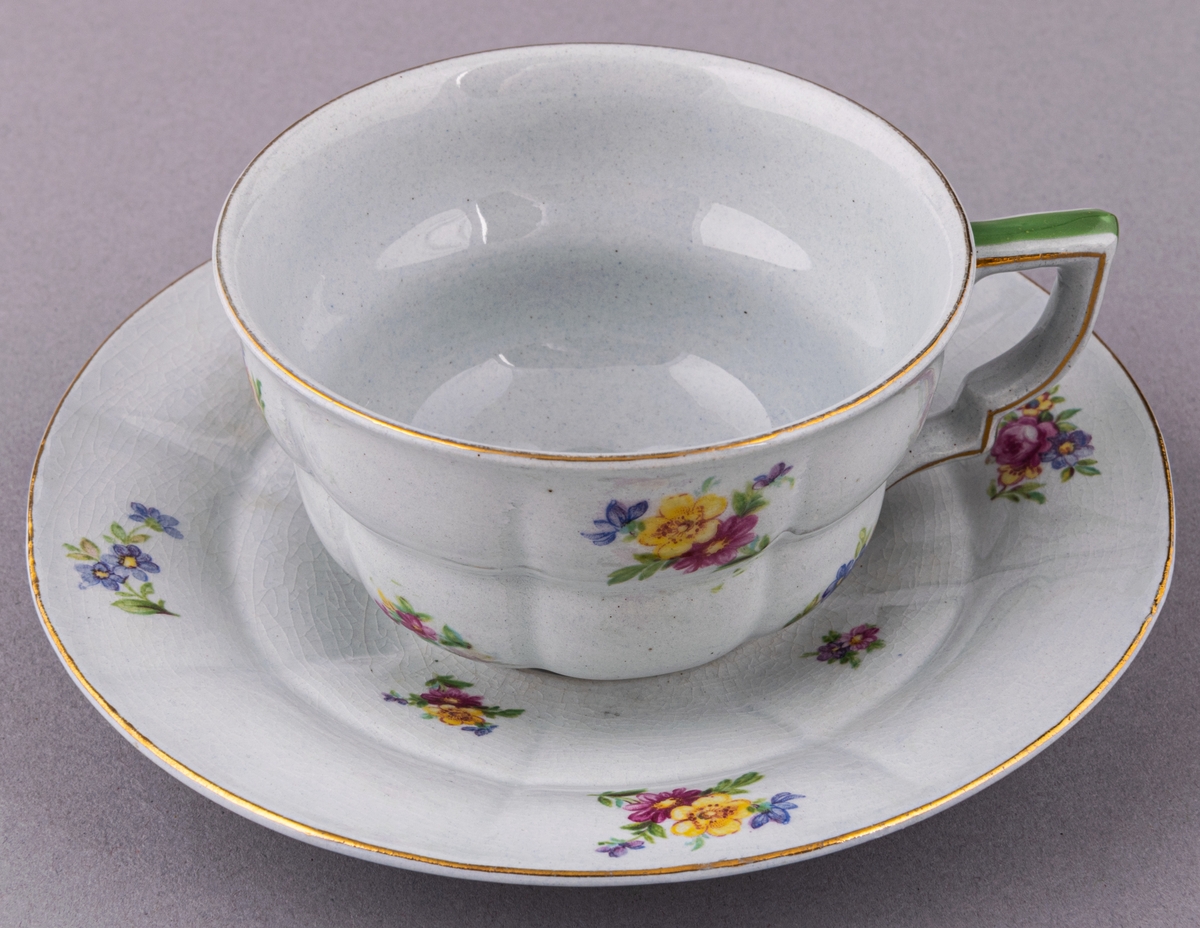 Kaffekopp med fat, i flintgods. Modelll AB, dekor Rosaslie. Ljusblå glasyr med blommönster. Skapad av Eugen Trost för Gefle Porslinsfabrik 1939.