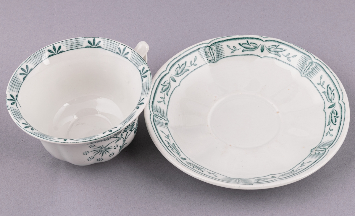 Kaffekopp med fat, i flintgods. Modell O, dekor Kerstin. Vit glasyr med grönt blommönster. Skapad av Arthur Percy för Gefle Porslinsfabrik 1933.