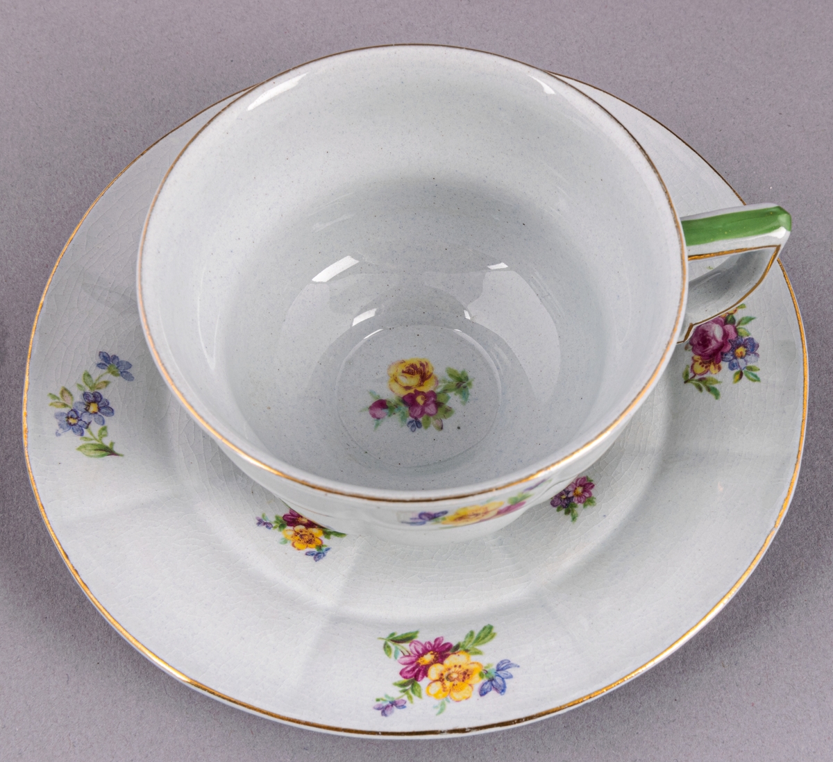 Kaffekopp med fat, i flintgods. Modelll AB, dekor Rosaslie. Ljusblå glasyr med blommönster. Skapad av Eugen Trost för Gefle Porslinsfabrik 1939.