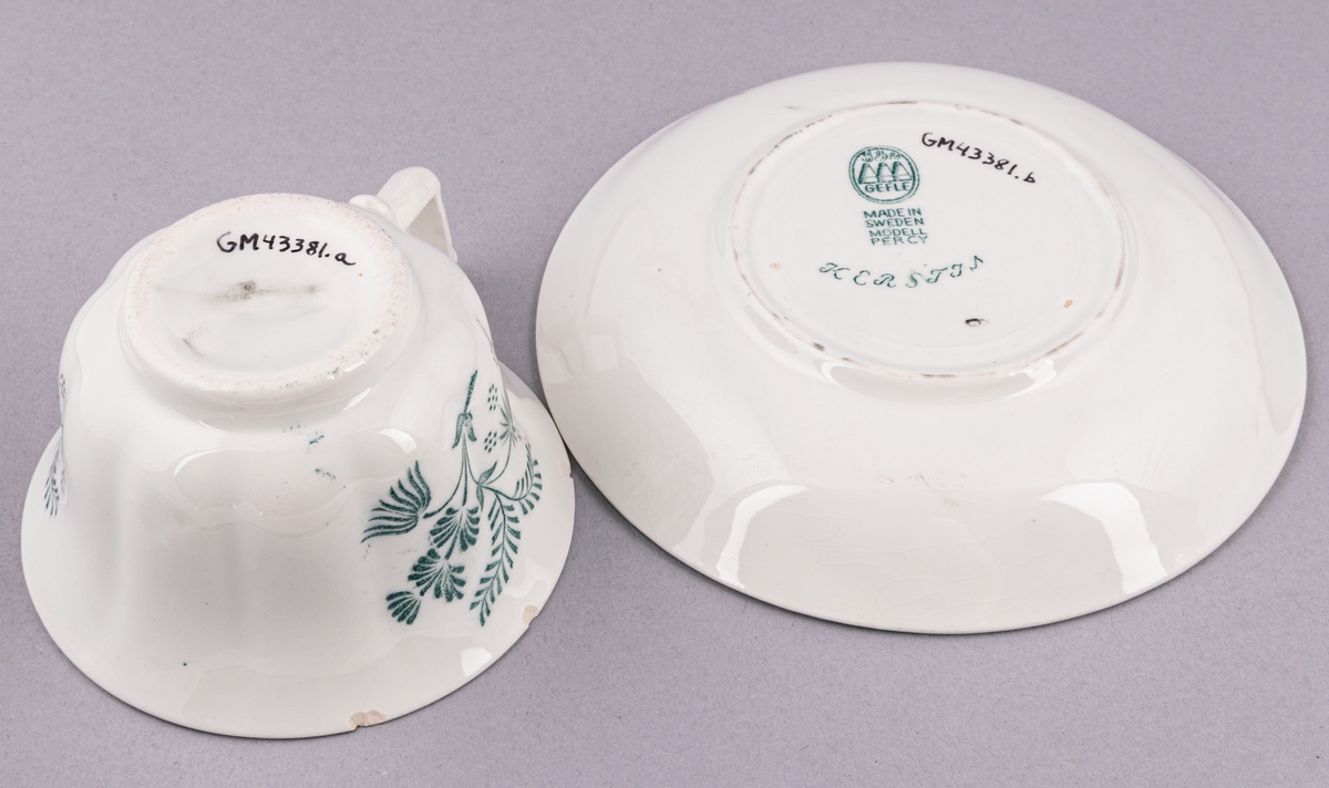 Kaffekopp med fat, i flintgods. Modell O, dekor Kerstin. Vit glasyr med grönt blommönster. Skapad av Arthur Percy för Gefle Porslinsfabrik 1933.