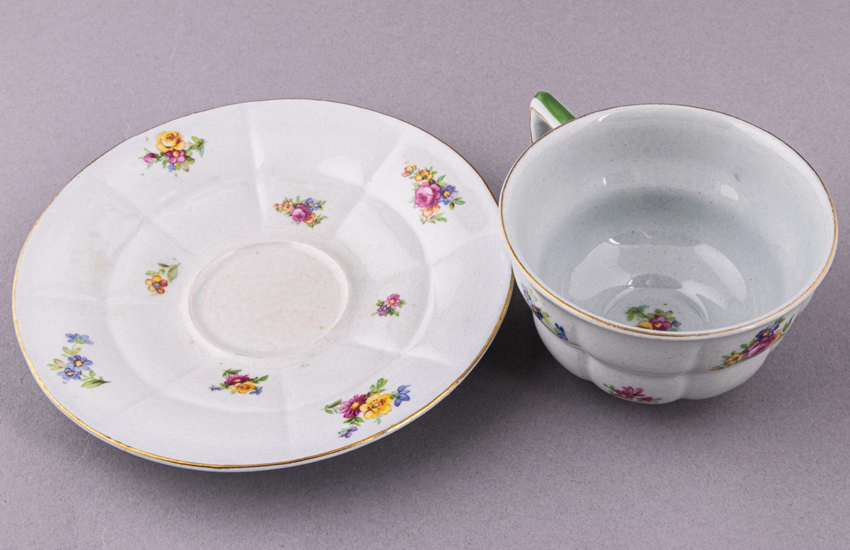 Kaffekopp med fat, i flintgods. Modelll AB, dekor Rosaslie. Ljusblå glasyr med blommönster. Skapad av Eugen Trost för Gefle Porslinsfabrik 1939.