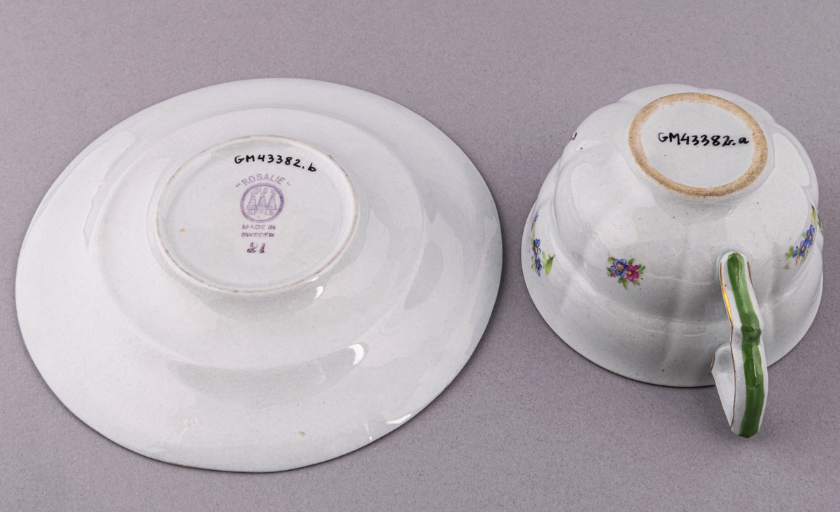 Kaffekopp med fat, i flintgods. Modelll AB, dekor Rosaslie. Ljusblå glasyr med blommönster. Skapad av Eugen Trost för Gefle Porslinsfabrik 1939.