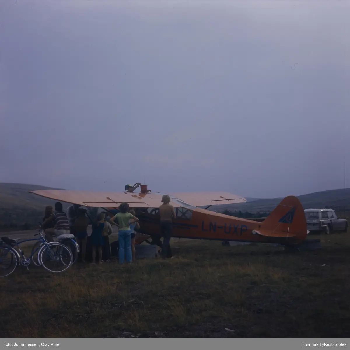 Foto av fly på flyplass i Båtsfjord

Mannen som fyller bensin bak flyet er Ivar Bryggari 

Gutt helt til venstre het Kjell Tore Tiberg 

På siden står teksten: LN-UXP

Foto trolig tatt på 1960/70-tallet