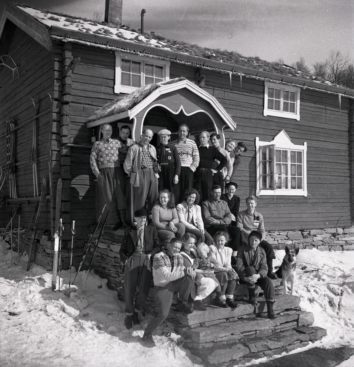 En grupp människor poserar på en trappa framför ett hus 1947 i Ramundberget.