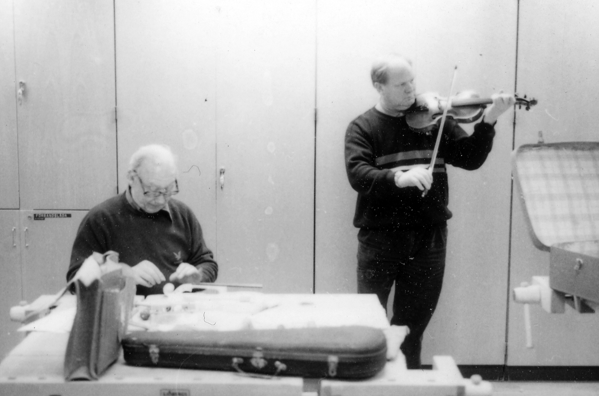 Fiolbyggarkurs i Fyllingeskolans slöjdsal, Halmstad under ledning av Thorsten Sandberg.
Motivtext foto 1: F d tryckeriägaren Sture Rydberg putsar på halsen.
Motivtext foto 2: Sture Rydberg t v och på fiol Anders Jägsell.
Motivtext foto 3: Thorsten Sandberg t h visar Kjell Pihl som gör en ny greppbräda till en trasig fiol.
Motivtext foto 4-5: Anders Bäckman skär det sista av spåret som ådern ska ligga i.
Motivtext foto 6: Anders Jägsell har limmat ihop botten och sarg och halsen.
Motivtext foto 7-9: Ove Lindahl och hans "arbetsplats". Han filar kanterna på locket. Botten och sarg ligger färdiga.
Motivext foto 10: Kjell Pihl arbetar med greppbräda av ebenholz.
Motitext foto 11: Thorsten Sandberg håller på att göra i ordning åskådningsmaterial till museets vandringsutställning.
Motivtext foto 12-14: Sture Rydberg slipar halsen. På hyvelbänken ligger lock, botten och mall och många redskap.
Motivtext foto 15-16: se neg nr 9-11. Foto 7-9.
Motivtext foto 17: Sture Rydberg.
Motivtext foto 18-19: Ove Lindahl.
Motivtext foto 20: Thorsten Sandberg.
Motivtext foto 21-22: Thorsten Sandberg hjälper Sture Rydberg. Halsens anslutning till fiolen riktas med en bräda.
Motivtext foto 23-29: Justering av basbjälken, som sitter limmad på insidan av locket. Thorsten Sandberg skär bort en del, knackar i träet och hör på ljudet.