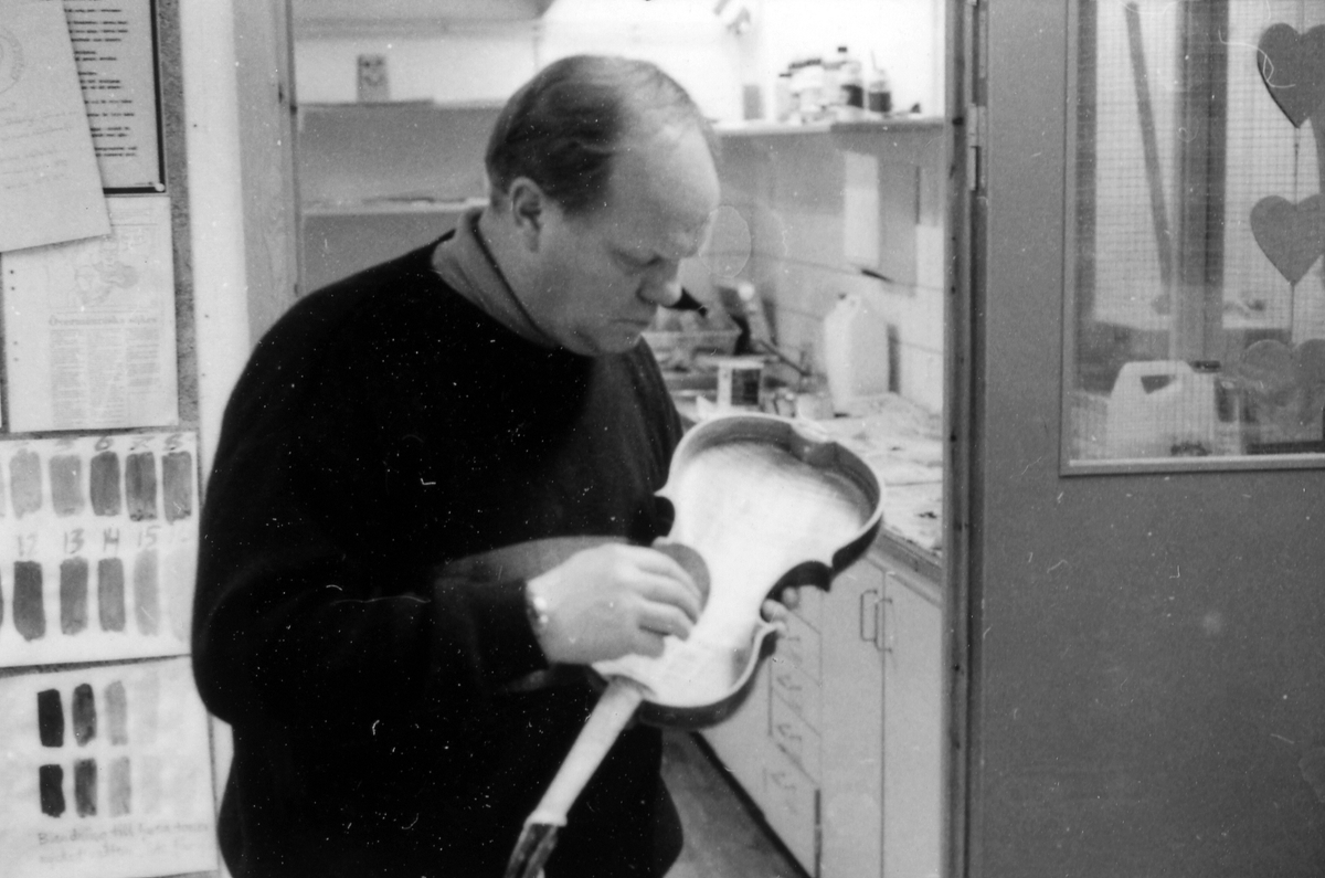 Fiolbyggarkurs i Fyllingeskolans slöjdsal, Halmstad under ledning av Thorsten Sandberg.
Motivtext foto 1: F d tryckeriägaren Sture Rydberg putsar på halsen.
Motivtext foto 2: Sture Rydberg t v och på fiol Anders Jägsell.
Motivtext foto 3: Thorsten Sandberg t h visar Kjell Pihl som gör en ny greppbräda till en trasig fiol.
Motivtext foto 4-5: Anders Bäckman skär det sista av spåret som ådern ska ligga i.
Motivtext foto 6: Anders Jägsell har limmat ihop botten och sarg och halsen.
Motivtext foto 7-9: Ove Lindahl och hans "arbetsplats". Han filar kanterna på locket. Botten och sarg ligger färdiga.
Motivext foto 10: Kjell Pihl arbetar med greppbräda av ebenholz.
Motitext foto 11: Thorsten Sandberg håller på att göra i ordning åskådningsmaterial till museets vandringsutställning.
Motivtext foto 12-14: Sture Rydberg slipar halsen. På hyvelbänken ligger lock, botten och mall och många redskap.
Motivtext foto 15-16: se neg nr 9-11. Foto 7-9.
Motivtext foto 17: Sture Rydberg.
Motivtext foto 18-19: Ove Lindahl.
Motivtext foto 20: Thorsten Sandberg.
Motivtext foto 21-22: Thorsten Sandberg hjälper Sture Rydberg. Halsens anslutning till fiolen riktas med en bräda.
Motivtext foto 23-29: Justering av basbjälken, som sitter limmad på insidan av locket. Thorsten Sandberg skär bort en del, knackar i träet och hör på ljudet.