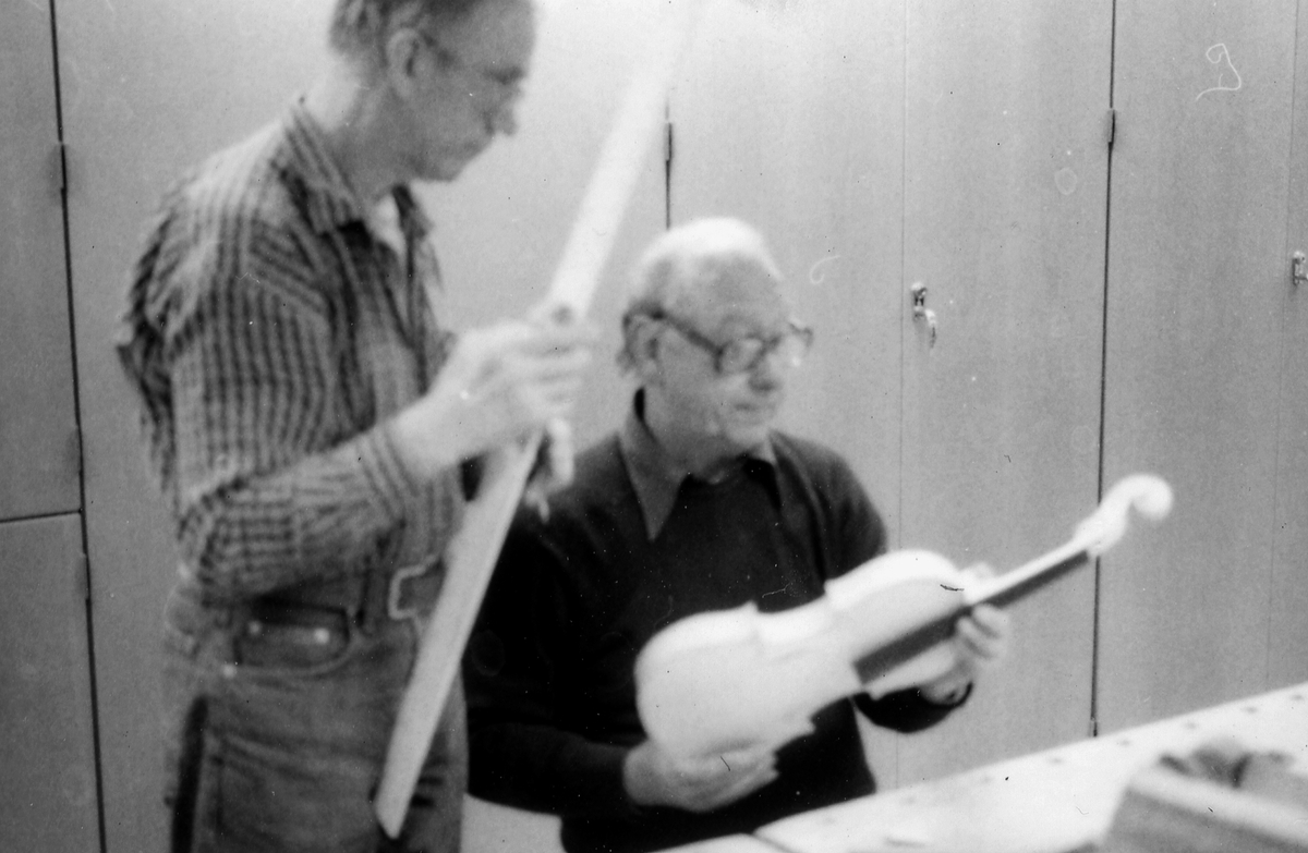 Fiolbyggarkurs i Fyllingeskolans slöjdsal, Halmstad under ledning av Thorsten Sandberg.
Motivtext foto 1: F d tryckeriägaren Sture Rydberg putsar på halsen.
Motivtext foto 2: Sture Rydberg t v och på fiol Anders Jägsell.
Motivtext foto 3: Thorsten Sandberg t h visar Kjell Pihl som gör en ny greppbräda till en trasig fiol.
Motivtext foto 4-5: Anders Bäckman skär det sista av spåret som ådern ska ligga i.
Motivtext foto 6: Anders Jägsell har limmat ihop botten och sarg och halsen.
Motivtext foto 7-9: Ove Lindahl och hans "arbetsplats". Han filar kanterna på locket. Botten och sarg ligger färdiga.
Motivext foto 10: Kjell Pihl arbetar med greppbräda av ebenholz.
Motitext foto 11: Thorsten Sandberg håller på att göra i ordning åskådningsmaterial till museets vandringsutställning.
Motivtext foto 12-14: Sture Rydberg slipar halsen. På hyvelbänken ligger lock, botten och mall och många redskap.
Motivtext foto 15-16: se neg nr 9-11. Foto 7-9.
Motivtext foto 17: Sture Rydberg.
Motivtext foto 18-19: Ove Lindahl.
Motivtext foto 20: Thorsten Sandberg.
Motivtext foto 21-22: Thorsten Sandberg hjälper Sture Rydberg. Halsens anslutning till fiolen riktas med en bräda.
Motivtext foto 23-29: Justering av basbjälken, som sitter limmad på insidan av locket. Thorsten Sandberg skär bort en del, knackar i träet och hör på ljudet.