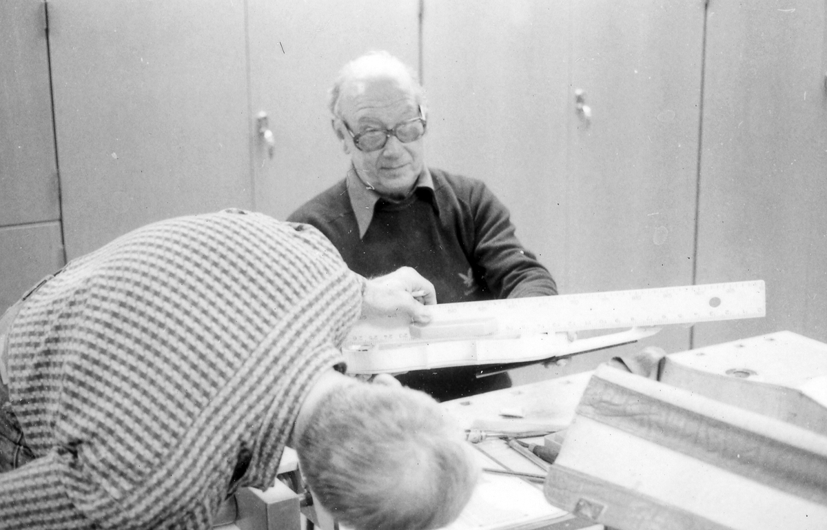 Fiolbyggarkurs i Fyllingeskolans slöjdsal, Halmstad under ledning av Thorsten Sandberg.
Motivtext foto 1: F d tryckeriägaren Sture Rydberg putsar på halsen.
Motivtext foto 2: Sture Rydberg t v och på fiol Anders Jägsell.
Motivtext foto 3: Thorsten Sandberg t h visar Kjell Pihl som gör en ny greppbräda till en trasig fiol.
Motivtext foto 4-5: Anders Bäckman skär det sista av spåret som ådern ska ligga i.
Motivtext foto 6: Anders Jägsell har limmat ihop botten och sarg och halsen.
Motivtext foto 7-9: Ove Lindahl och hans "arbetsplats". Han filar kanterna på locket. Botten och sarg ligger färdiga.
Motivext foto 10: Kjell Pihl arbetar med greppbräda av ebenholz.
Motitext foto 11: Thorsten Sandberg håller på att göra i ordning åskådningsmaterial till museets vandringsutställning.
Motivtext foto 12-14: Sture Rydberg slipar halsen. På hyvelbänken ligger lock, botten och mall och många redskap.
Motivtext foto 15-16: se neg nr 9-11. Foto 7-9.
Motivtext foto 17: Sture Rydberg.
Motivtext foto 18-19: Ove Lindahl.
Motivtext foto 20: Thorsten Sandberg.
Motivtext foto 21-22: Thorsten Sandberg hjälper Sture Rydberg. Halsens anslutning till fiolen riktas med en bräda.
Motivtext foto 23-29: Justering av basbjälken, som sitter limmad på insidan av locket. Thorsten Sandberg skär bort en del, knackar i träet och hör på ljudet.
