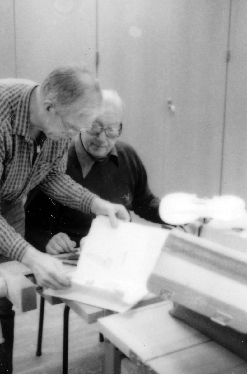 Fiolbyggarkurs i Fyllingeskolans slöjdsal, Halmstad under ledning av Thorsten Sandberg.
Motivtext foto 1: F d tryckeriägaren Sture Rydberg putsar på halsen.
Motivtext foto 2: Sture Rydberg t v och på fiol Anders Jägsell.
Motivtext foto 3: Thorsten Sandberg t h visar Kjell Pihl som gör en ny greppbräda till en trasig fiol.
Motivtext foto 4-5: Anders Bäckman skär det sista av spåret som ådern ska ligga i.
Motivtext foto 6: Anders Jägsell har limmat ihop botten och sarg och halsen.
Motivtext foto 7-9: Ove Lindahl och hans "arbetsplats". Han filar kanterna på locket. Botten och sarg ligger färdiga.
Motivext foto 10: Kjell Pihl arbetar med greppbräda av ebenholz.
Motitext foto 11: Thorsten Sandberg håller på att göra i ordning åskådningsmaterial till museets vandringsutställning.
Motivtext foto 12-14: Sture Rydberg slipar halsen. På hyvelbänken ligger lock, botten och mall och många redskap.
Motivtext foto 15-16: se neg nr 9-11. Foto 7-9.
Motivtext foto 17: Sture Rydberg.
Motivtext foto 18-19: Ove Lindahl.
Motivtext foto 20: Thorsten Sandberg.
Motivtext foto 21-22: Thorsten Sandberg hjälper Sture Rydberg. Halsens anslutning till fiolen riktas med en bräda.
Motivtext foto 23-29: Justering av basbjälken, som sitter limmad på insidan av locket. Thorsten Sandberg skär bort en del, knackar i träet och hör på ljudet.