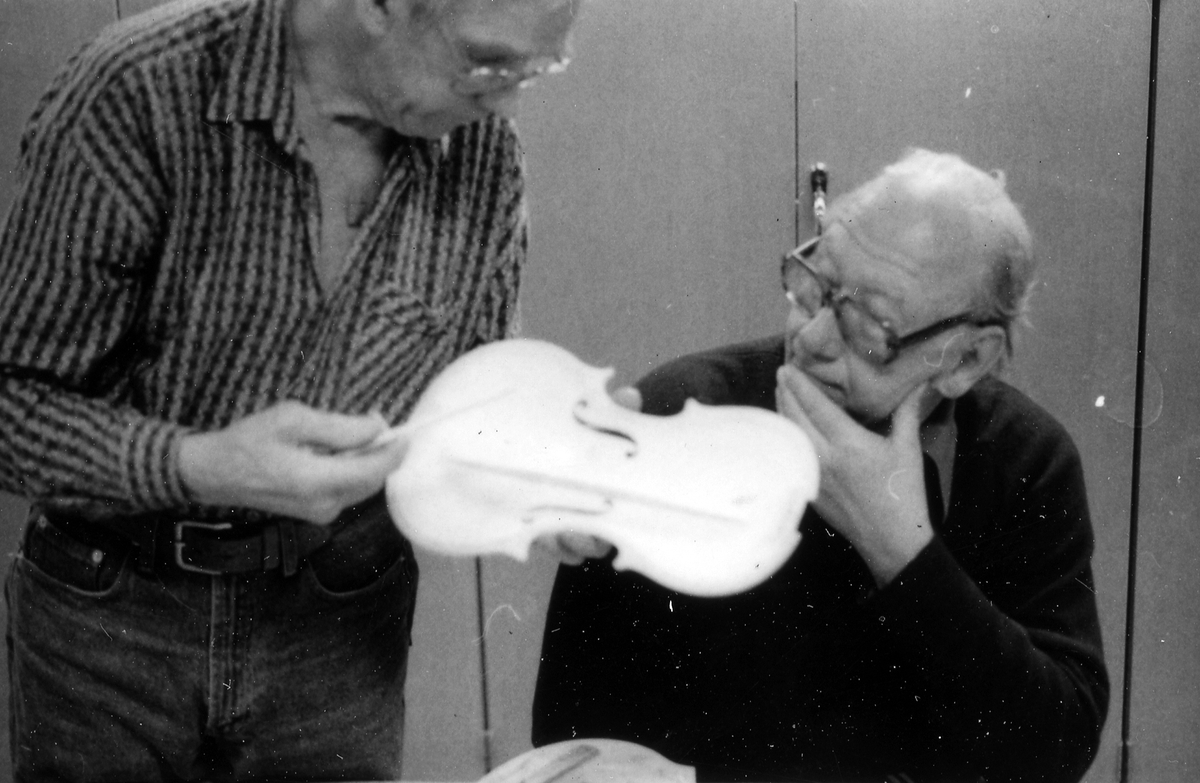 Fiolbyggarkurs i Fyllingeskolans slöjdsal, Halmstad under ledning av Thorsten Sandberg.
Motivtext foto 1: F d tryckeriägaren Sture Rydberg putsar på halsen.
Motivtext foto 2: Sture Rydberg t v och på fiol Anders Jägsell.
Motivtext foto 3: Thorsten Sandberg t h visar Kjell Pihl som gör en ny greppbräda till en trasig fiol.
Motivtext foto 4-5: Anders Bäckman skär det sista av spåret som ådern ska ligga i.
Motivtext foto 6: Anders Jägsell har limmat ihop botten och sarg och halsen.
Motivtext foto 7-9: Ove Lindahl och hans "arbetsplats". Han filar kanterna på locket. Botten och sarg ligger färdiga.
Motivext foto 10: Kjell Pihl arbetar med greppbräda av ebenholz.
Motitext foto 11: Thorsten Sandberg håller på att göra i ordning åskådningsmaterial till museets vandringsutställning.
Motivtext foto 12-14: Sture Rydberg slipar halsen. På hyvelbänken ligger lock, botten och mall och många redskap.
Motivtext foto 15-16: se neg nr 9-11. Foto 7-9.
Motivtext foto 17: Sture Rydberg.
Motivtext foto 18-19: Ove Lindahl.
Motivtext foto 20: Thorsten Sandberg.
Motivtext foto 21-22: Thorsten Sandberg hjälper Sture Rydberg. Halsens anslutning till fiolen riktas med en bräda.
Motivtext foto 23-29: Justering av basbjälken, som sitter limmad på insidan av locket. Thorsten Sandberg skär bort en del, knackar i träet och hör på ljudet.