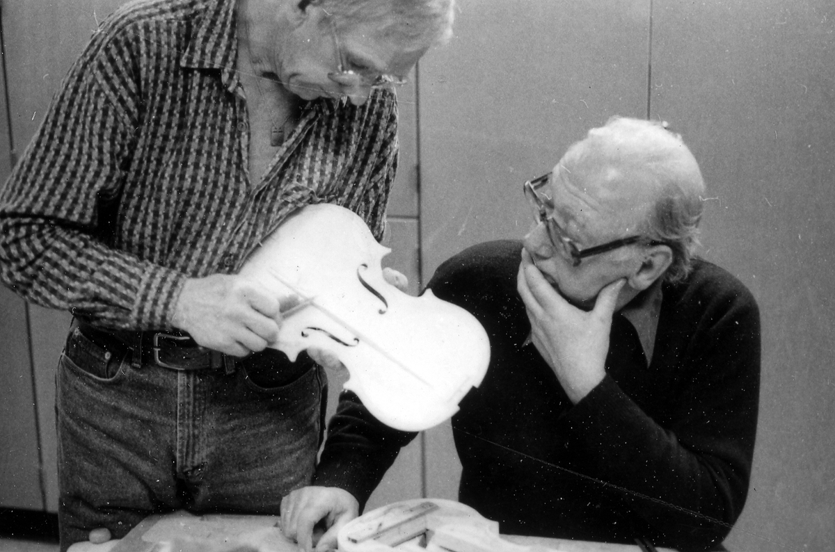 Fiolbyggarkurs i Fyllingeskolans slöjdsal, Halmstad under ledning av Thorsten Sandberg.
Motivtext foto 1: F d tryckeriägaren Sture Rydberg putsar på halsen.
Motivtext foto 2: Sture Rydberg t v och på fiol Anders Jägsell.
Motivtext foto 3: Thorsten Sandberg t h visar Kjell Pihl som gör en ny greppbräda till en trasig fiol.
Motivtext foto 4-5: Anders Bäckman skär det sista av spåret som ådern ska ligga i.
Motivtext foto 6: Anders Jägsell har limmat ihop botten och sarg och halsen.
Motivtext foto 7-9: Ove Lindahl och hans "arbetsplats". Han filar kanterna på locket. Botten och sarg ligger färdiga.
Motivext foto 10: Kjell Pihl arbetar med greppbräda av ebenholz.
Motitext foto 11: Thorsten Sandberg håller på att göra i ordning åskådningsmaterial till museets vandringsutställning.
Motivtext foto 12-14: Sture Rydberg slipar halsen. På hyvelbänken ligger lock, botten och mall och många redskap.
Motivtext foto 15-16: se neg nr 9-11. Foto 7-9.
Motivtext foto 17: Sture Rydberg.
Motivtext foto 18-19: Ove Lindahl.
Motivtext foto 20: Thorsten Sandberg.
Motivtext foto 21-22: Thorsten Sandberg hjälper Sture Rydberg. Halsens anslutning till fiolen riktas med en bräda.
Motivtext foto 23-29: Justering av basbjälken, som sitter limmad på insidan av locket. Thorsten Sandberg skär bort en del, knackar i träet och hör på ljudet.