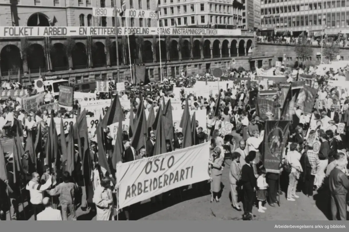 1. mai 1990. På Youngstorget i Oslo. Banner foran: Oslo Arbeiderparti. Bak: Folket i arbeid - en rettferdig fordeling- stans innstramningspolitikken.