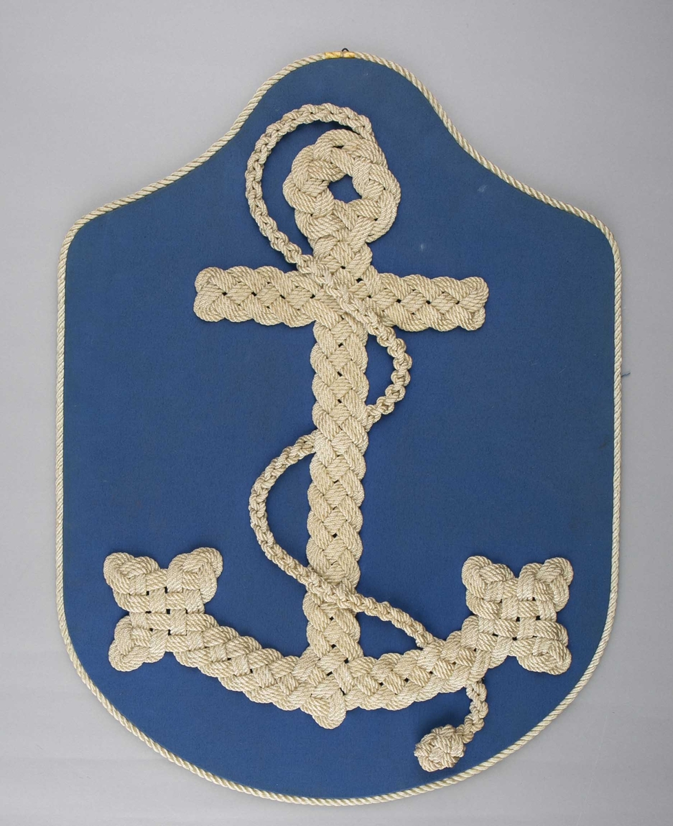 Knutearbeid montert på treplater. Flettet anker av tau montert på treplate trukket med blå tekstil.