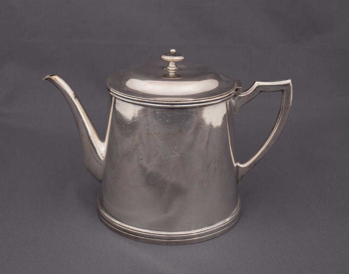 Del av BDS serveringssett. Stor kaffekanne med hank, tut og lokk, preget med logoen til Det Bergenske Dampskibsselskab.