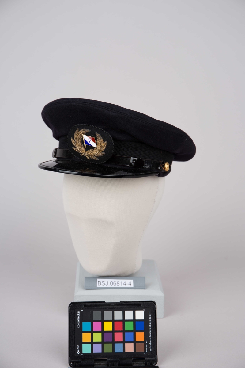 Uniformslue med skygge samt emaljert luemerke.