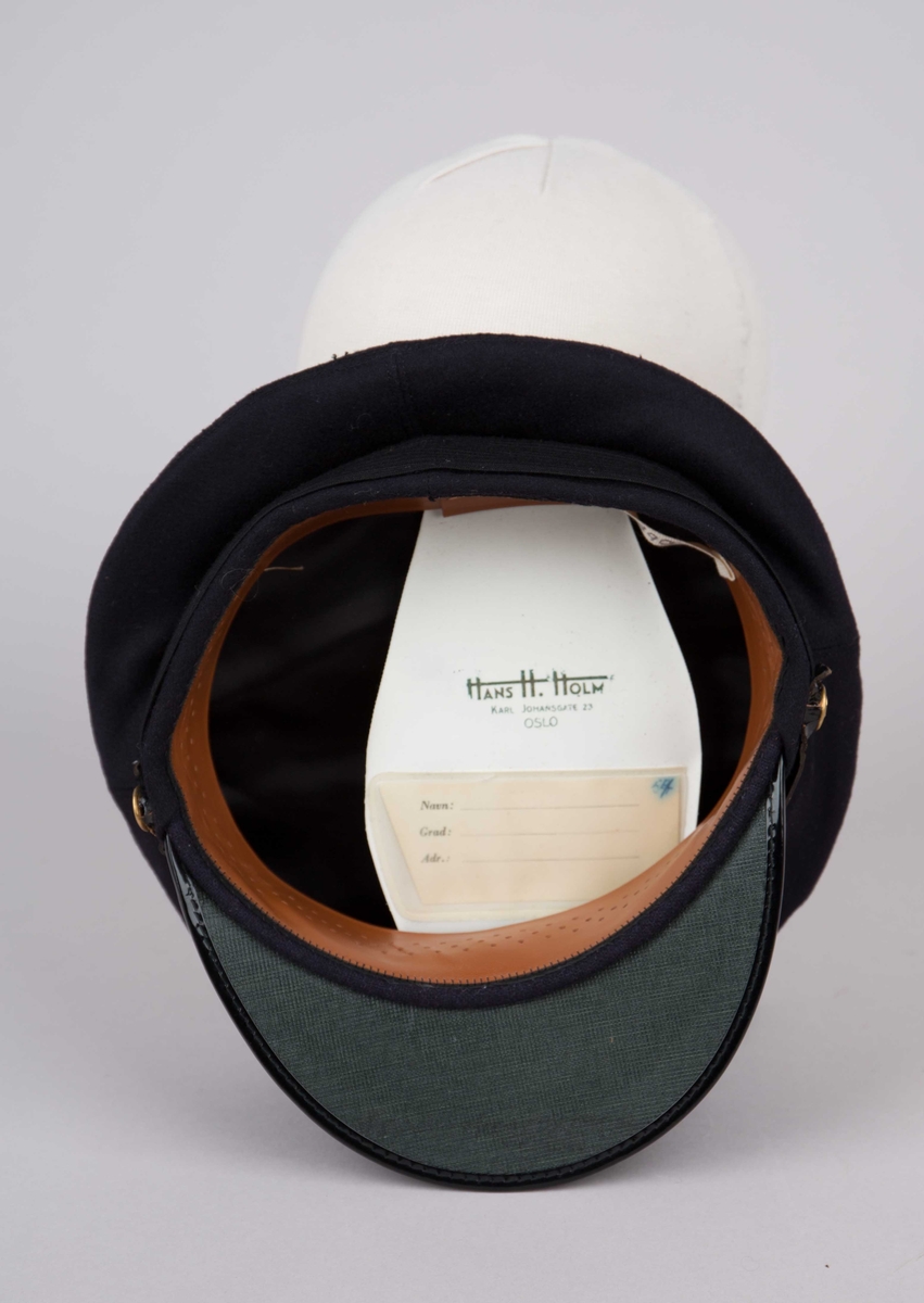 Uniformslue med skygge samt emaljert luemerke.