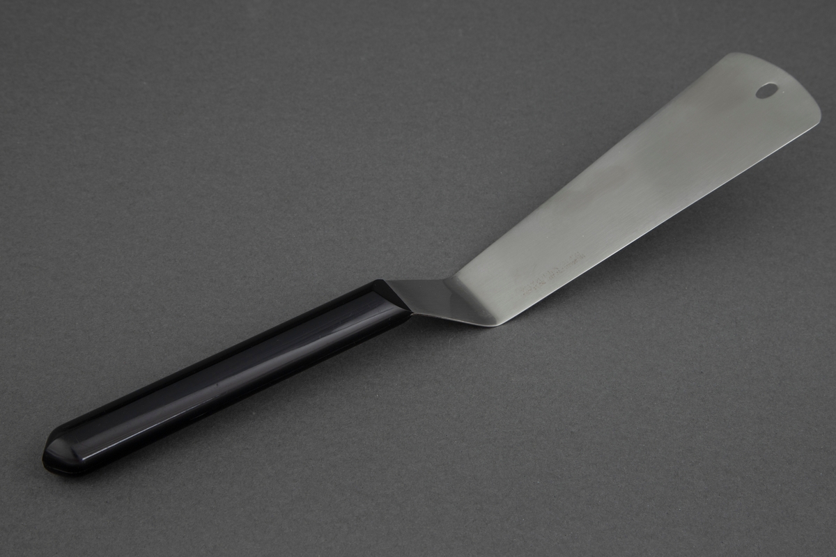 Stekespade i rustfritt stål med svart, kantete nylonskaft. Skaftet er festet rett til bladet .Utstanset oval øverst i bladet for oppheng.