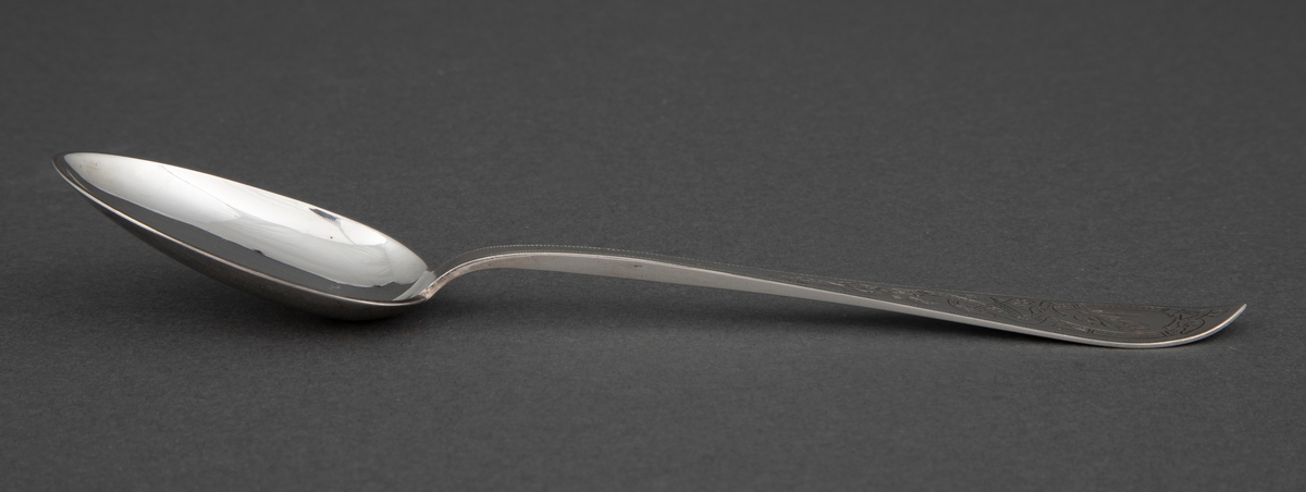 Spiseskje i sølv. Spisst, eggformet skjeblad og skaft som tiltar i bredde mot skaftenden som har spiss og lett oppbøyd avslutning. Dekor med to fabeldyr og bladranker.