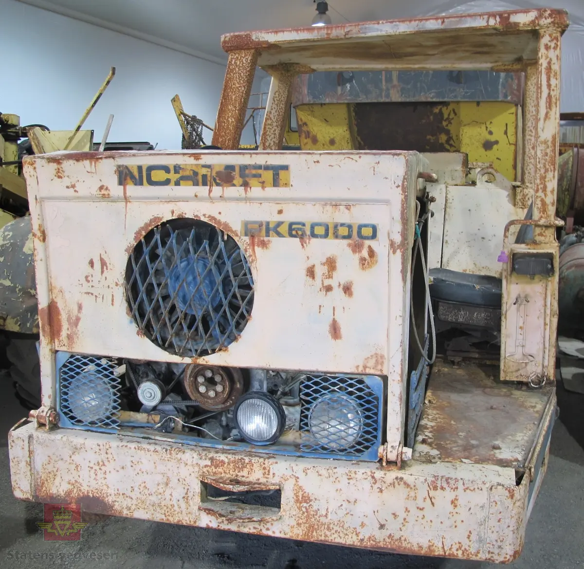 Normet PK 6000 D. 24 tonns gul dumper med 4 hjul, 2 akslinger. 6-sylindret luftavkjølt 9,6 liters Deutz dieselmotor med betegnelsen F6L 413 FW som yter 139 hk. Motoren har motornummer 6581711. Rammestyrt med 3 gir fremover, og revers. Dumperens toppfart er på 25 km/t. Har dumperkasse på 7 m3.