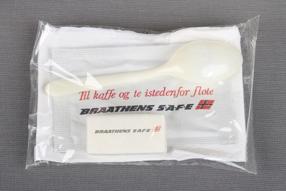 Eske fra servering om bord flyvning. Esken inneholder en kaffekopp og en liten pakke med serviett, melkepulver til kaffe/te, plastskje, og sukkerbit.