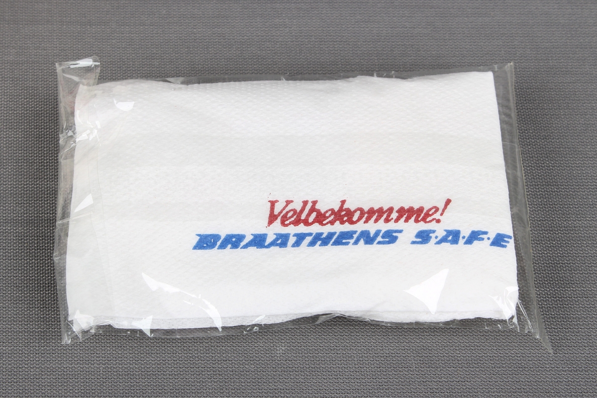 Eske fra servering om bord flyvning. Esken inneholder en kaffekopp og en liten pakke med serviett, melkepulver til kaffe/te, plastskje, og sukkerbit.