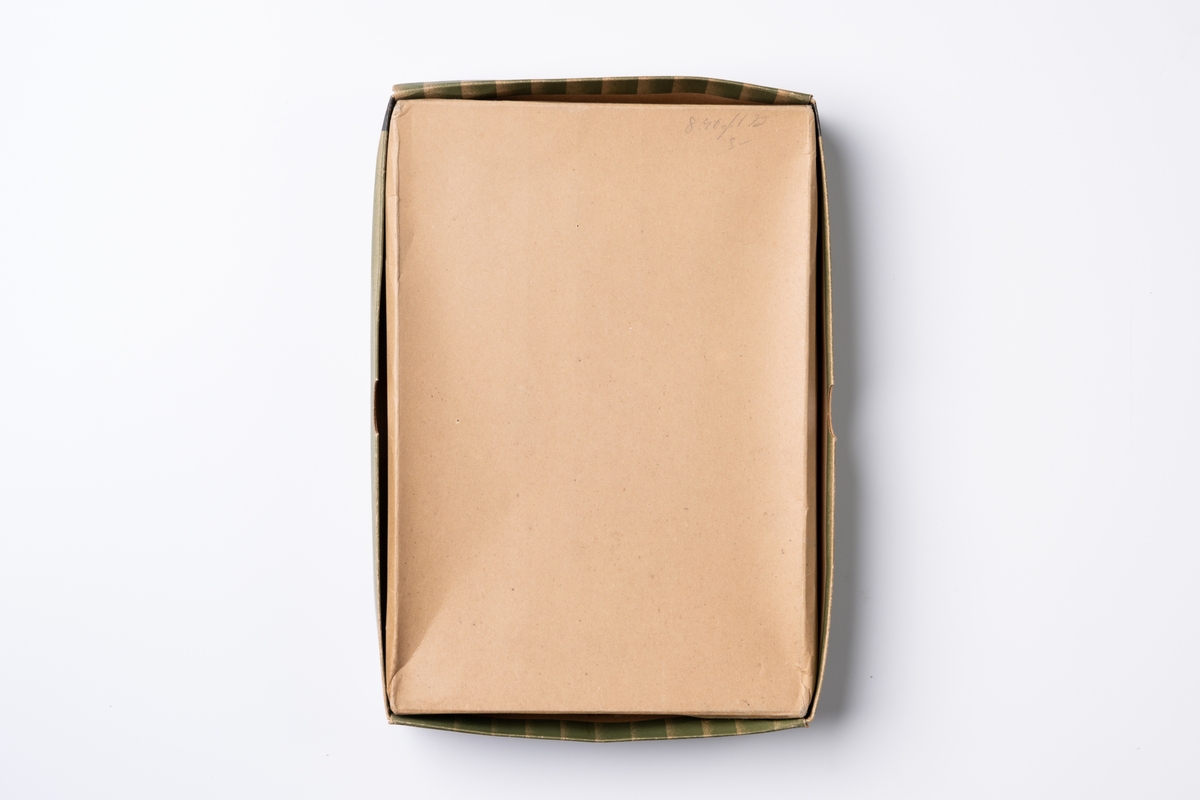Kartong för damstrumpor av märket Nivella med låda och lock. Förpackningen är av papper med tryck på utsidan i färgerna grönt, beige och svart. På locket tryckt text: "DAMSTRUMPOR nivella". Innanför lockets ena kant är tryckt text: "SNAP QUICK ÅKERLUND ÅR & RAUSING FÖRPACKNINGSFÖRETAGET S 2".

Lådan är inredd med vaxat papper och en kartongbit med pappersbanderoll med tryckt text: "nivella strumpan". I lådan finns också lösa två pappersetiketter med tvättråd och tryckt text: "Natursilke nivella strumpan". Etiketterna var vid förvärvstillfället fastklistrade på de två strumpparen som hör till kartongen.
