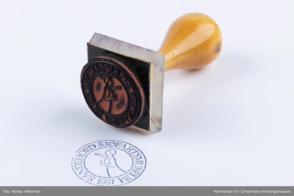 Stempel med trehåndtak med teksten SANDEFJORD SJØFARTSMUSEUM 1957