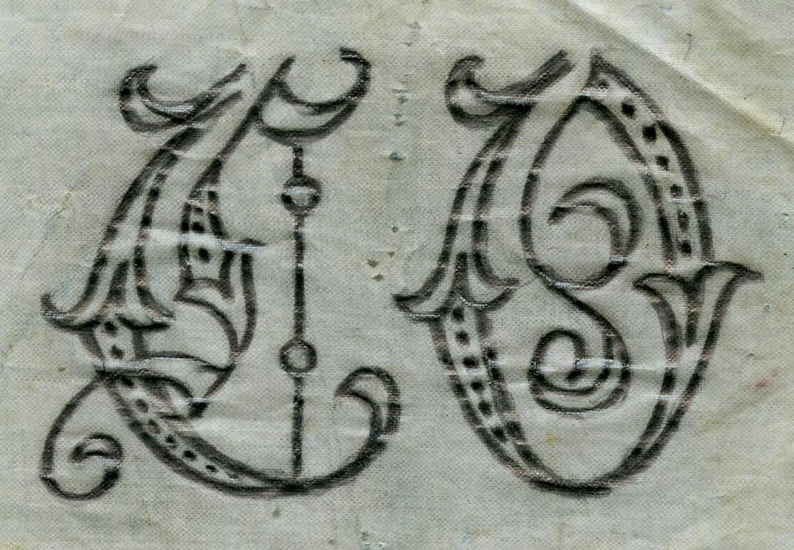 Broderimönster, ljusblått/grått papper, förvaras i ett ljusgrått kuvert. Okänd ålder. Kuvertet märkt med blyerts; "Monogram E.O". Motiv: olika monogram i rött och svart; "EO", "EM" samt "GERD". Papperna är något nötta. Del av en samling textilmönster från samma donation, förvaras i en mapp (C25324_1).