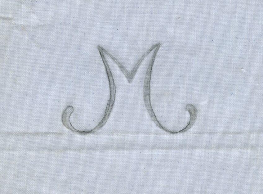 Broderimönster, ljusblått/grått papper, 11 st. i olika storlekar. Okänd ålder. Motiv: olika monogram; "M" och "MG" i olika varianter och konstellationer. Papperna något nötta, en del med permanenta veck efter att ha legat vikta under lång tid. Del av en samling textilmönster från samma donation, förvaras i en mapp (C25324_1).