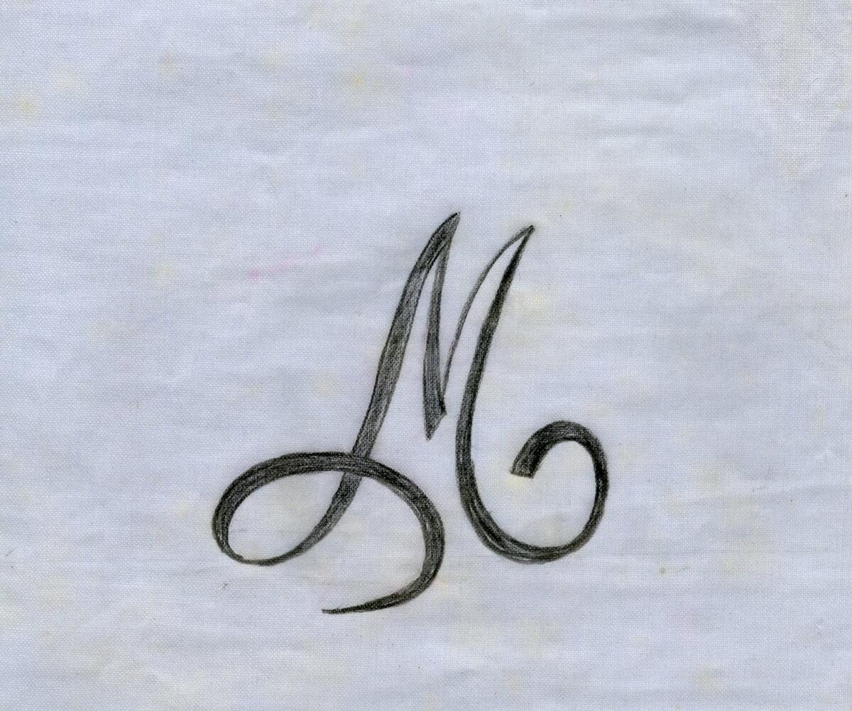 Broderimönster, ljusblått/grått papper, 11 st. i olika storlekar. Okänd ålder. Motiv: olika monogram; "M" och "MG" i olika varianter och konstellationer. Papperna något nötta, en del med permanenta veck efter att ha legat vikta under lång tid. Del av en samling textilmönster från samma donation, förvaras i en mapp (C25324_1).