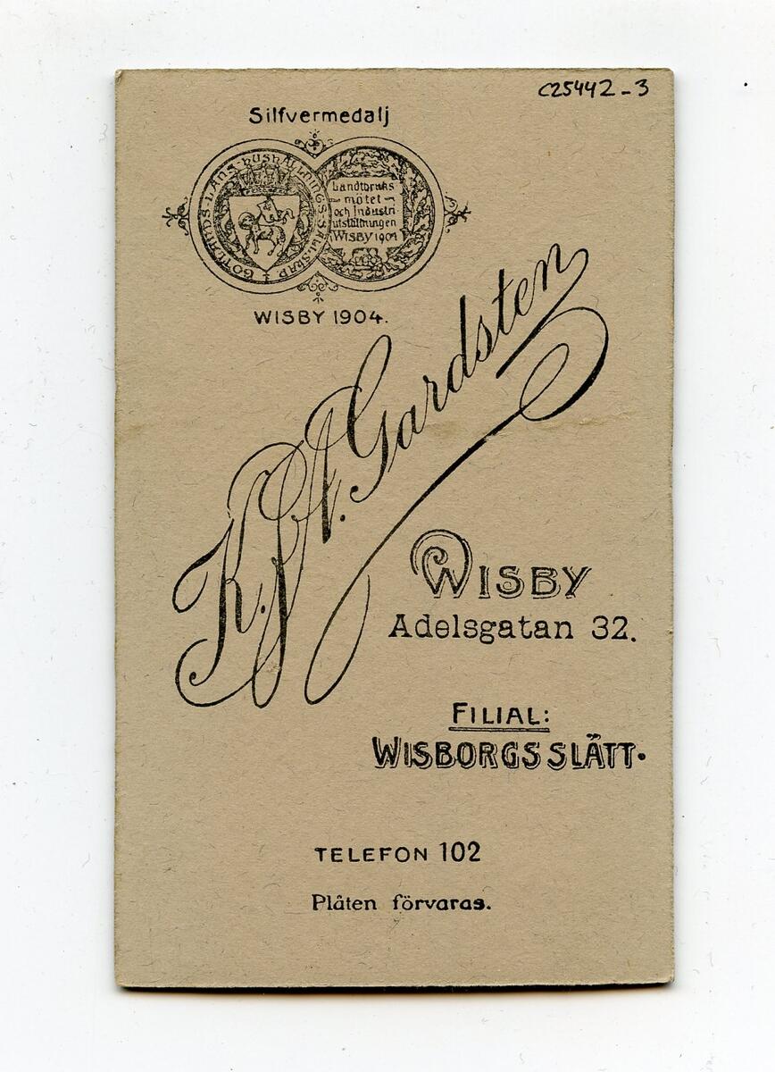 Porträttfotografi i visitkortsformat, tidigt 1900-tal. Bilden föreställer en oidentifierad man med ljust hår och mustasch. Han är klädd i mörk kostym, vit skjorta och ljus slips. Fotograf: K.J.A. Gardsten i Visby. Del av en samling porträttfotografier från okänd givare.