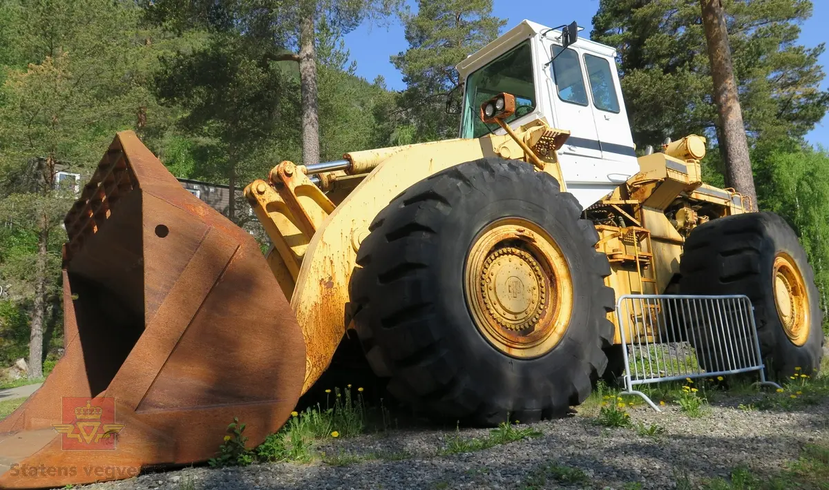 International H-400C Payloader. Hjullaster på 4 hjul, antatt 4-hjuls drift. Gul og svart. Motoren er en turboladet V12 Cummins type VT1710C-635. Dette er en 4-takts diesel med et cylindervolum på 1710 cu. in. (28 liter), Effekt 473.5 kw (635 hp). Skuffa rommer ni kubikkmeter.
Girkasse fra International Harvester, modellbetegnelse P-600S (to-trinns). Merking fra produsent og første bruker.