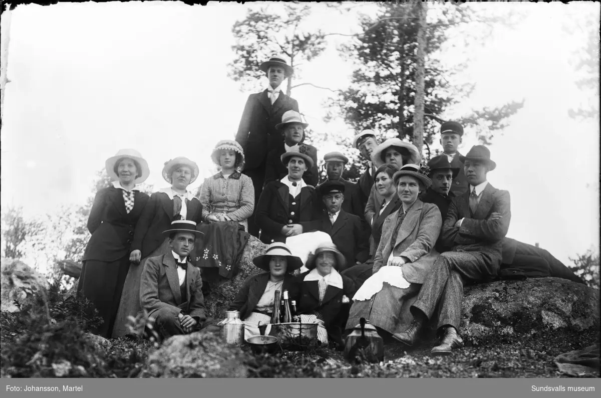 Midsommarfirande med utflyktsförtäring vid gården "Kampåkern", Sörfors. Gruppbild med bland andra familjerna Perssons och Grafströms.