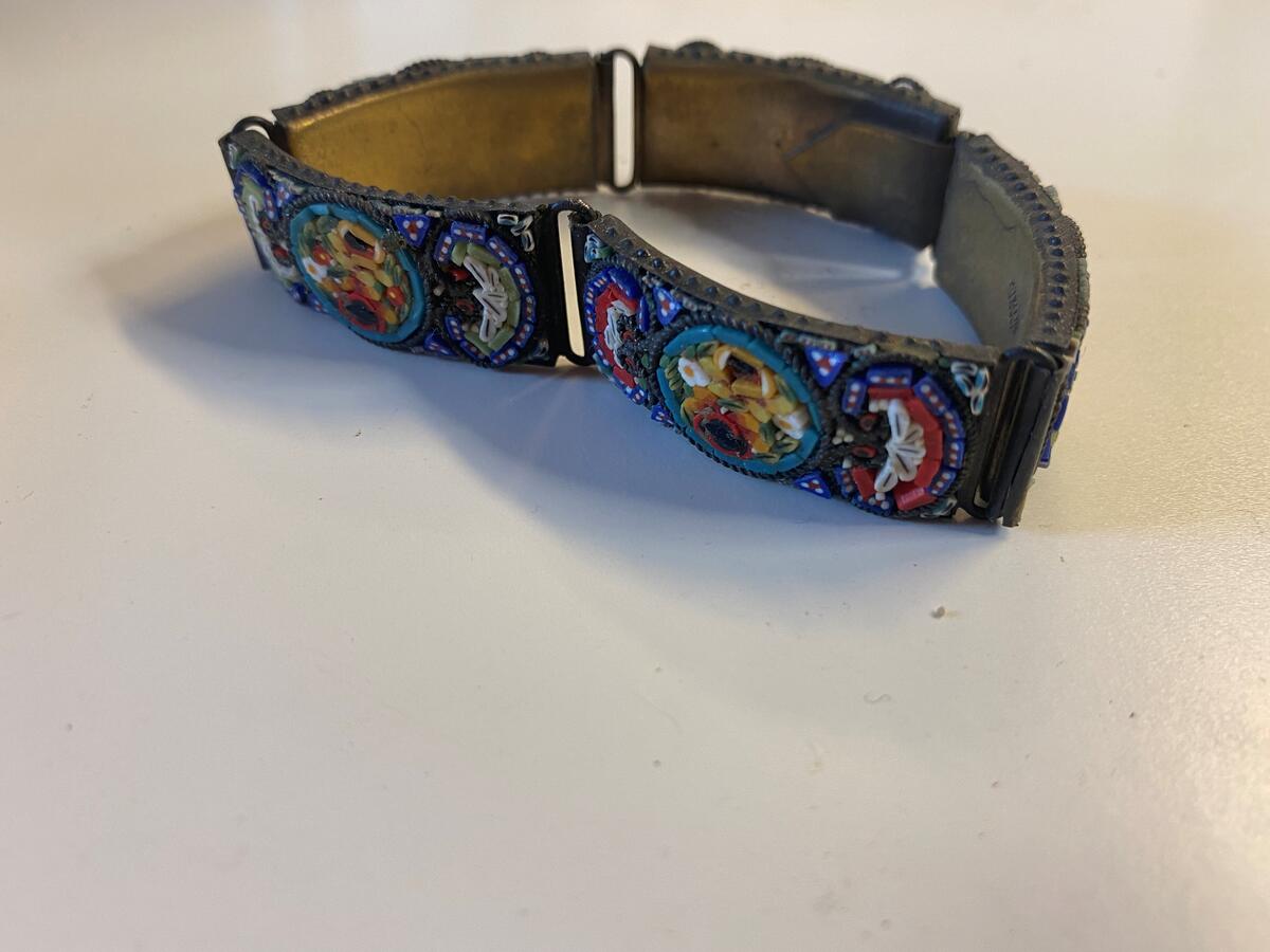 Armband med mosaikdekor föreställande blommor. Gulmetall. På baksida stämplad: "Made in Italy". 20 cm långt.