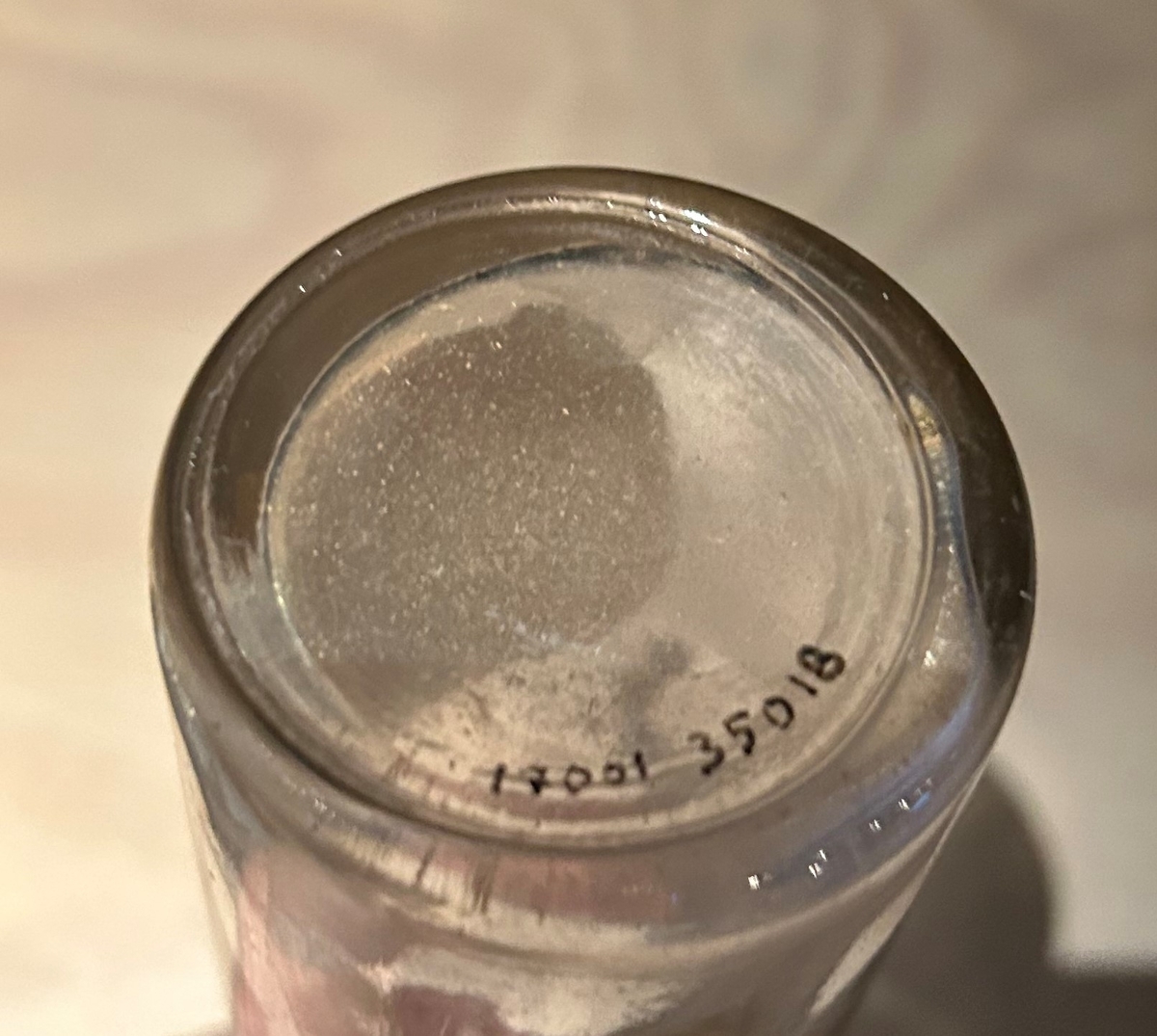 Flaska av ofärgat glas för förvaring av grädde. Hög smal hals. Kapsyl saknas. Oval pappersetikett i gul och orange med text: "Grädde steriliserad Hållbar ren naturprodukt 12 % fett" i det gula fältet, och "Karlstadsortens mejeriförening Karlstad" samt "KM" med en cirkel omkring, i det orangea fältet.