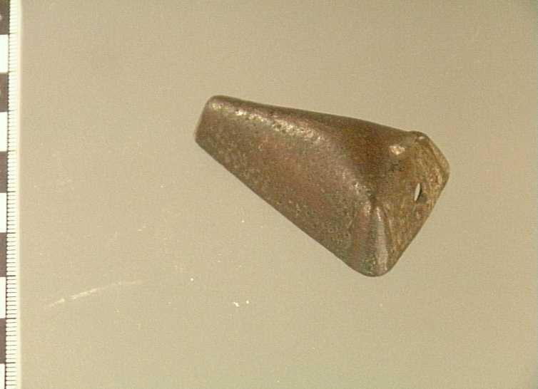 Enkel punktdekor, slitet
av brons, djurhuvudformat, längd 50, br. 31, h. 19 mm. Typ lik nr: 518. Men hål i nacken, (botten med nål saknas). Ena sidan något inböjd. Från västergarn, skänkt av scholaris martin nyman, 1886.