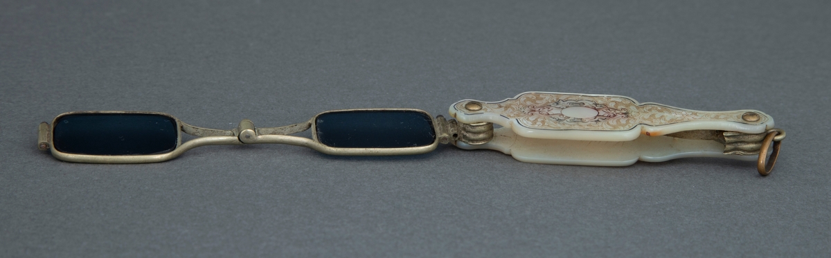 Sammenleggbar stanglorgnett i perlemorsholder. Holderens yttersider er dekorert med innrissede akantusblader på skrafert bunn og med en lyre i midten. Selve brillene er innfattet i en tynn rektangulær metallramme med avrundede hjørner. Glasset er dyptgrønt. Brillene kan ved et fjærende midtledd legges dobbelt før de skyves inn i holderen.