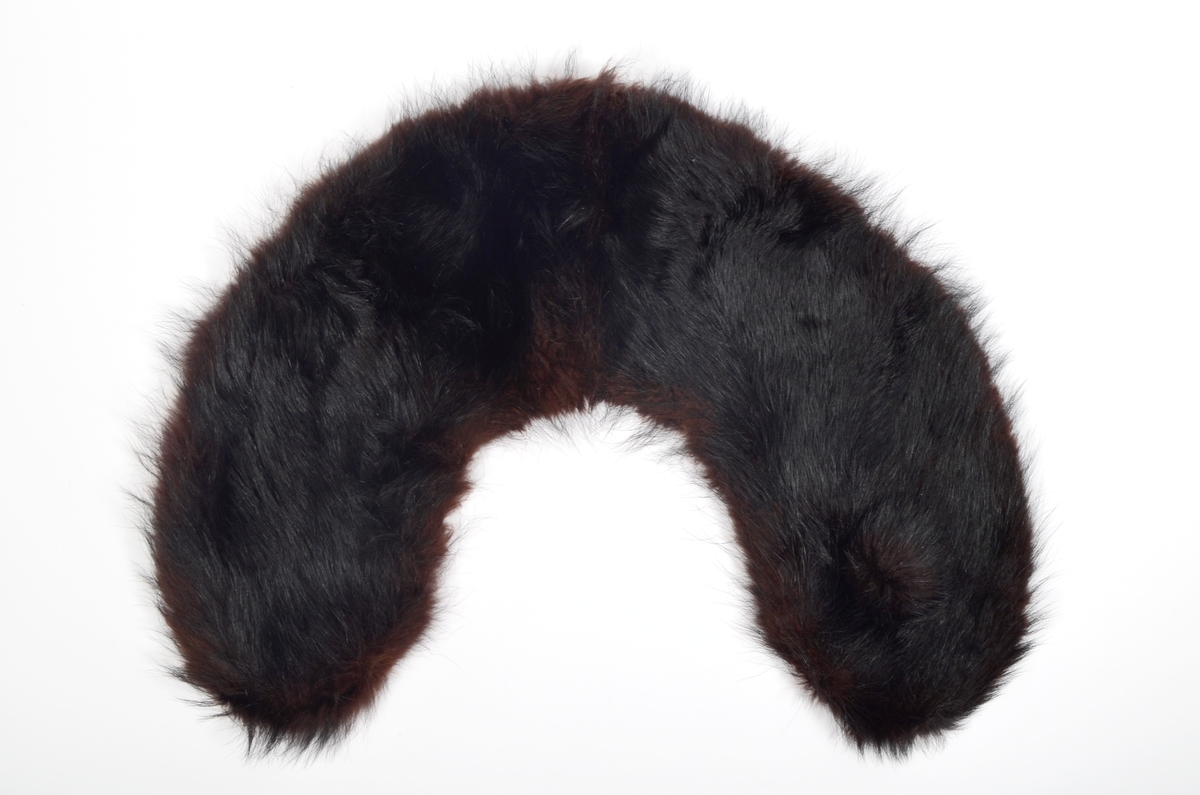 Løs, buet krage i brunsvart pels fôret med svart silkestoff.
