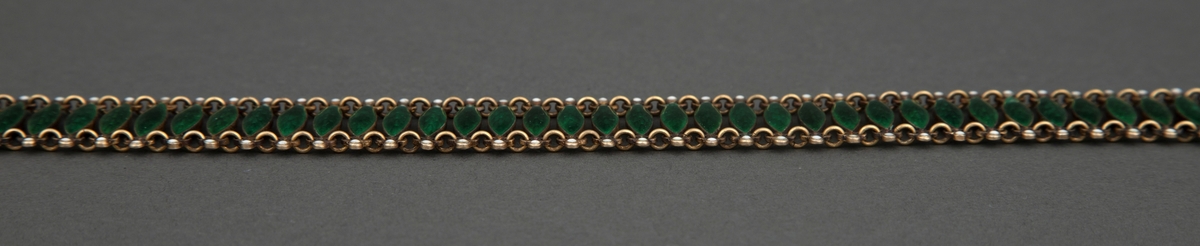 Halsband satt sammen av 72 tverrstaver dekket av grønn, halvtransparent emalje over guillochering. Leddenes form er spissoval med trepassformet utvidelse ved hver ende med huller for bøyler som holder leddene sammen og ytterst en "perle" i hvit emalje. Bakside og bøyler er av forgylt sølv. Hektelås til lukking av smykket.