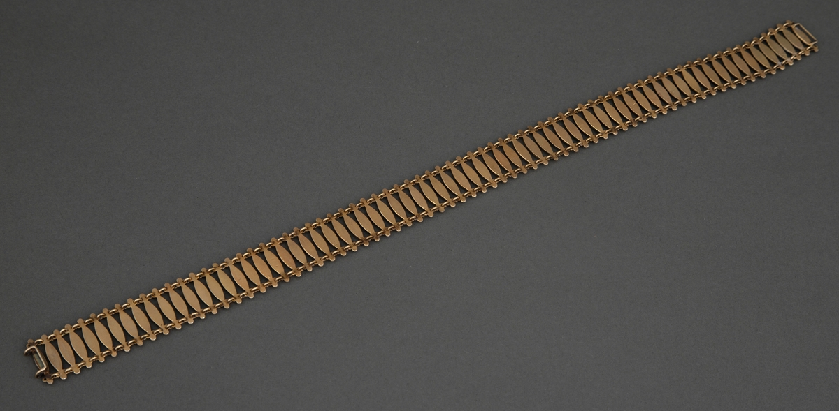 Halsband satt sammen av 72 tverrstaver dekket av grønn, halvtransparent emalje over guillochering. Leddenes form er spissoval med trepassformet utvidelse ved hver ende med huller for bøyler som holder leddene sammen og ytterst en "perle" i hvit emalje. Bakside og bøyler er av forgylt sølv. Hektelås til lukking av smykket.