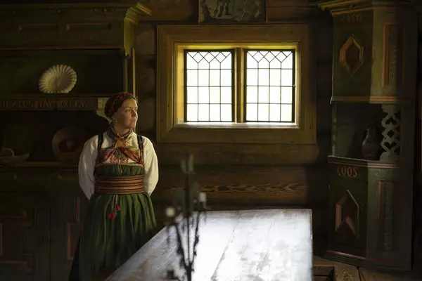 Kvinne i bunad står ved siden av et bord