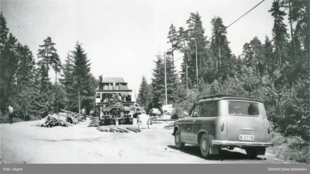 Trafo-transport fra Ise til Hasle i 1963. Bilen har kjørt seg fast i gjørma, Småbergkrysset. Boggien og tilhengeren veide tilsammen 46 tonn! Trafoen veide 140 tonn!! I forgrunnen varebil med kjennetegn B-2219.
 av merket Hillman Husky.