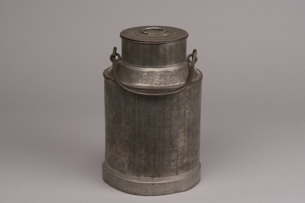 Cylindrisk mjölkanna med lock av bleckplåt.
Den avsmalnade halsen är försedd med ett bygelhandtag i stål. Även locket har ett pålött handtag.