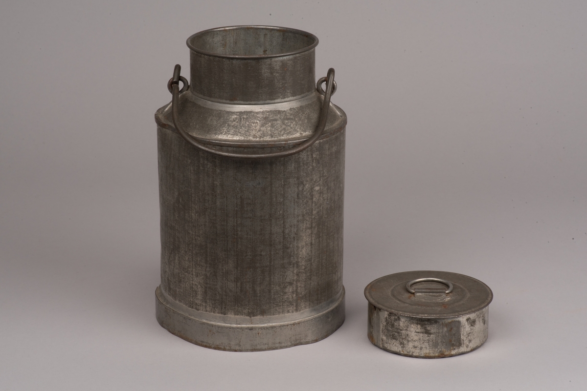Cylindrisk mjölkanna med lock av bleckplåt.
Den avsmalnade halsen är försedd med ett bygelhandtag i stål. Även locket har ett pålött handtag.